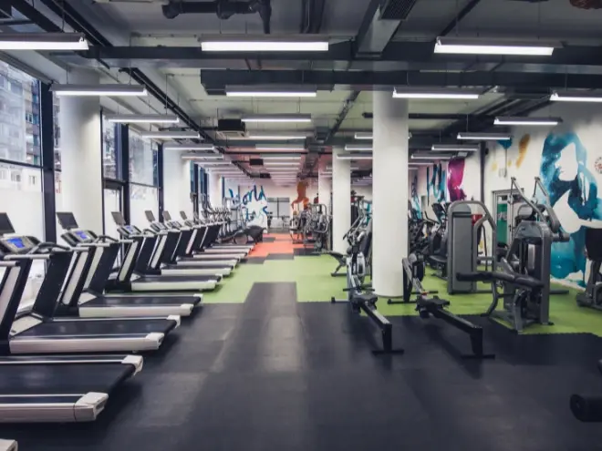 Spacious gym with fitness equipment and people exercising.