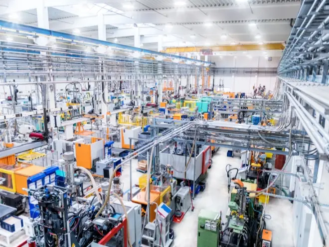 Industrial warehouse with machinery, piping systems, and production lines.